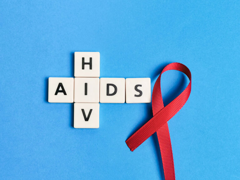 red ribbon with aids and hiv crosswords against blue background