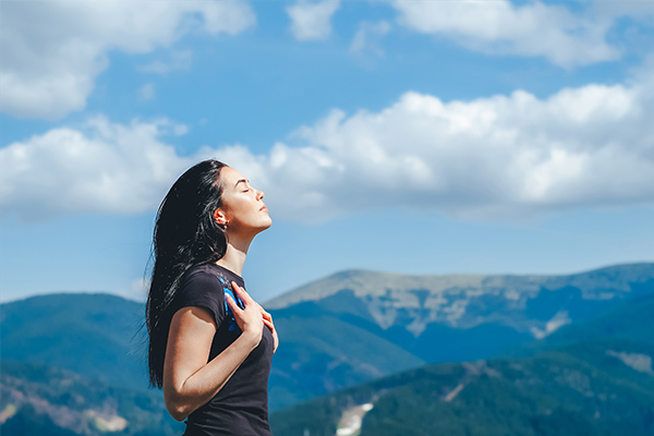 Young woman meditating with a landscape full of mountains in the background