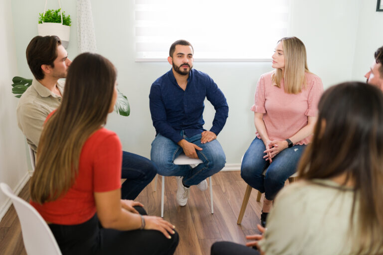 Group of people sitting in a circle socializing and discussing their problems